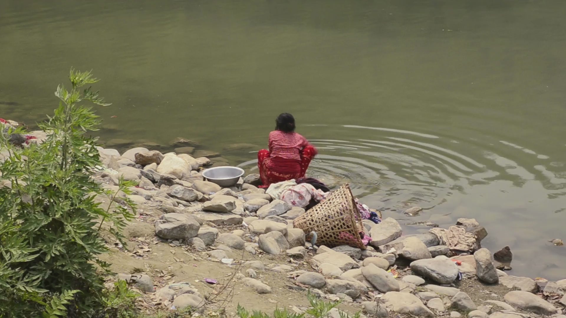 Load video: Woman doing laundry by the river.